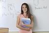 An image showing a girl holding an Anatomy and Physiology book, with a whiteboard behind that has chemistry concepts written on it