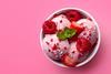 Three pink ice cream scoops covered in raspberries and strawberries