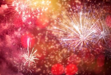 A photograph showing red, orange and blue fireworks during a night-time display.