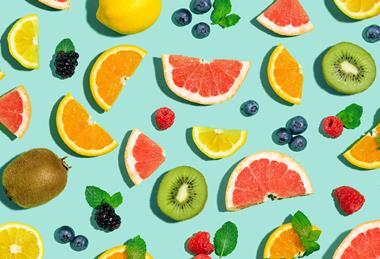A photographic illustration of different fruits, whole and sliced, on a turquoise background