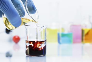 Pouring light yellow iron chloride solution into a beaker of clear potassium thiocyanate solution causing a chemical reaction changing the colour of the liquid to dark red