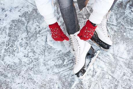 Someone tying up their ice skates while sitting on ice