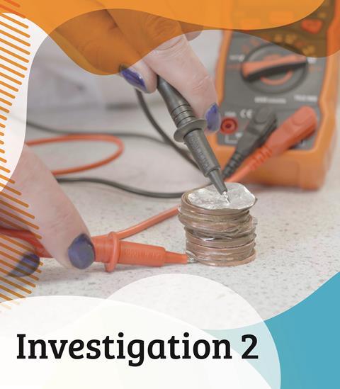 A scientist applies a voltmeter to a coin battery on a work bench, to test how different electrolytes perform